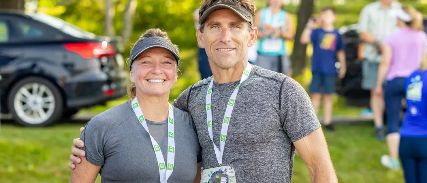 Two U N E employees pose together after running the Beach to Beacon 10K Road Race