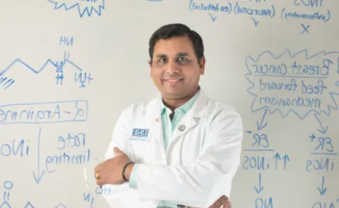 Portrait of Sri Mohan against a whiteboard with chemical formulas